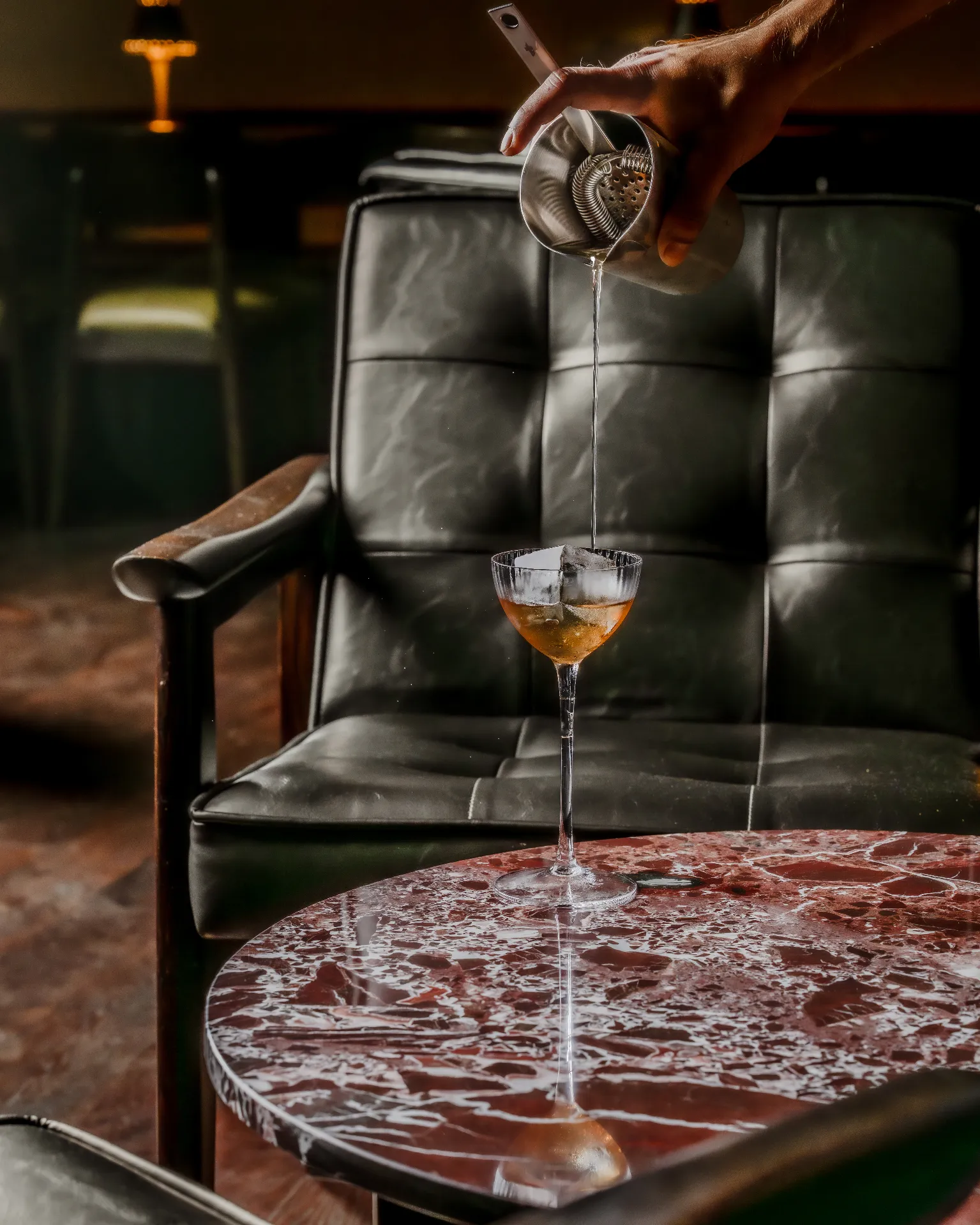 Cocktail being poured over a marble table in a lounge
