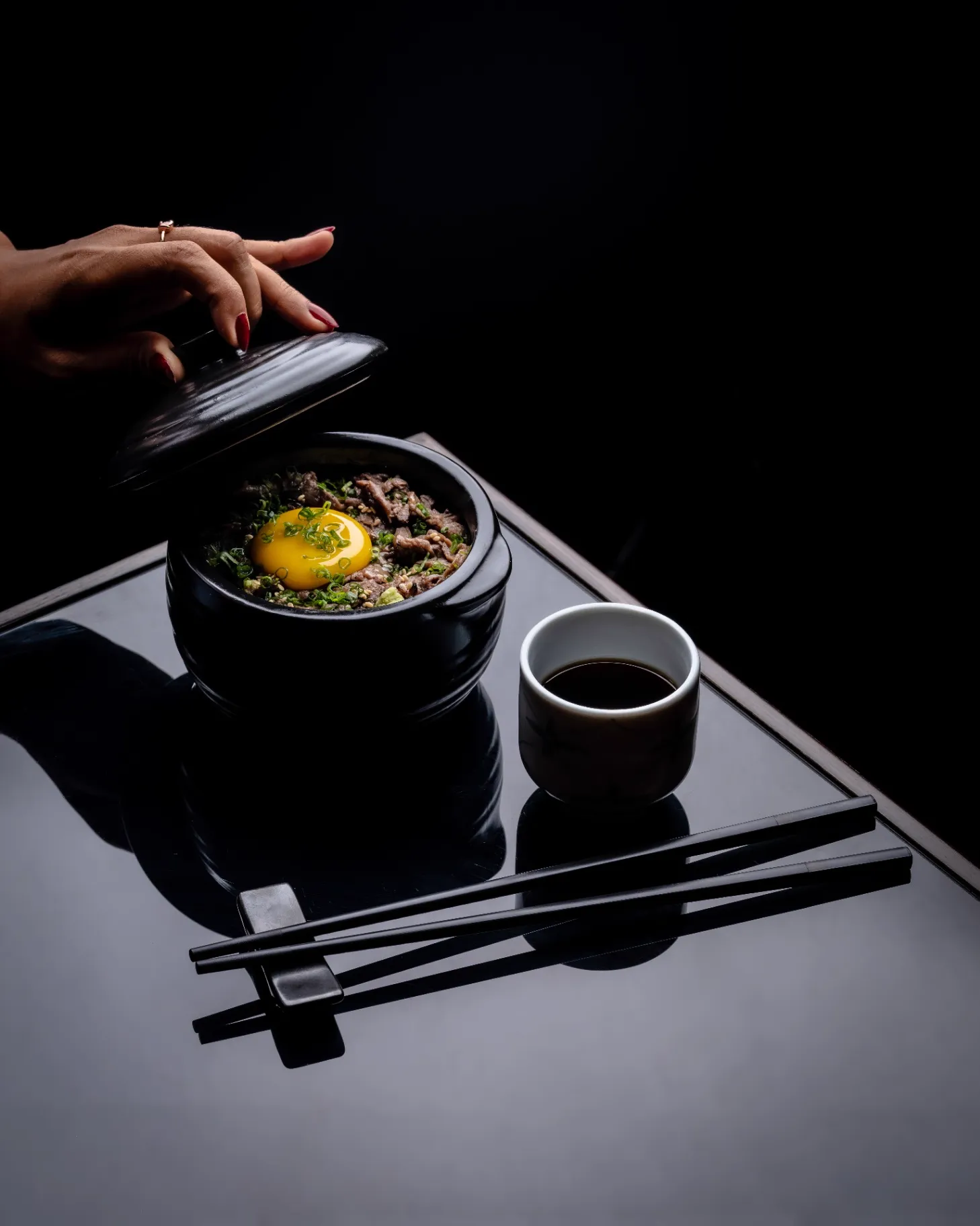 Beef bibimbap in a black stone pot with a runny egg yolk