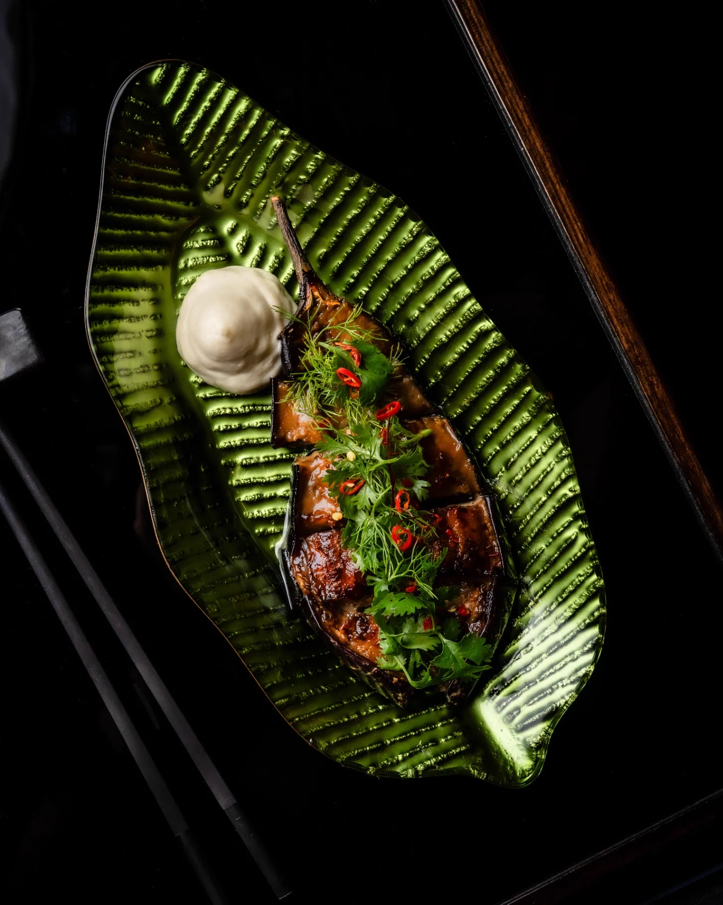 Miso-glazed eggplant with herbs on a banana leaf plate